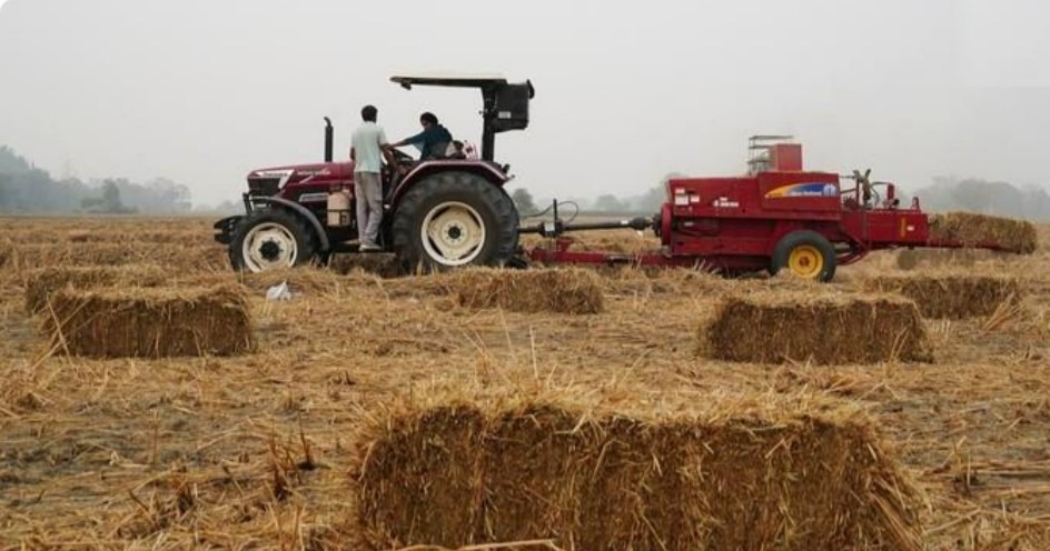 Tractor and baler collecting rice straw after harvest